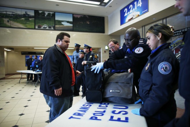 Members of the Transportation Security Administration check a passenger's bags with N.J. Transit Police to secure mass transit for the Super Bowl XLVIII, in Secaucus